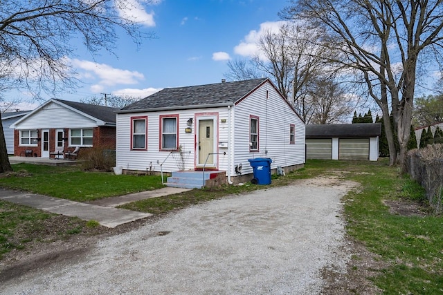 bungalow with a front lawn, an outdoor structure, driveway, and fence