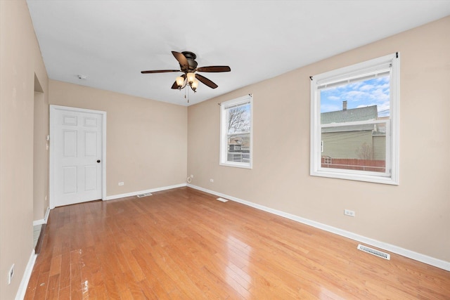 empty room with visible vents, ceiling fan, light wood-type flooring, and baseboards