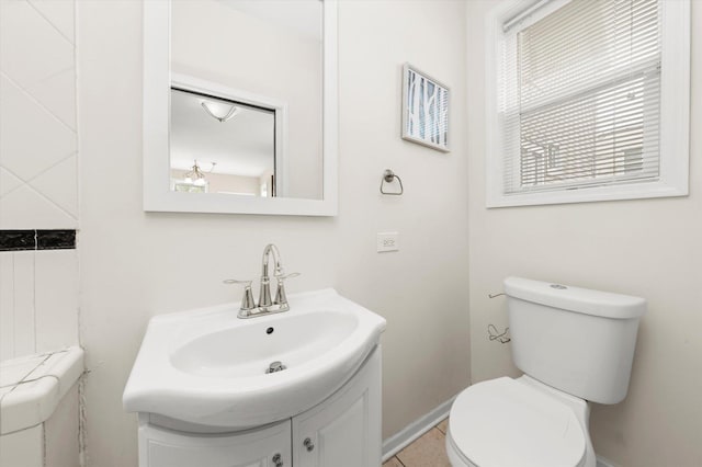 half bathroom featuring toilet, tile patterned floors, vanity, and baseboards