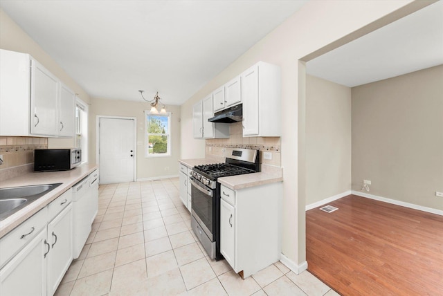 kitchen featuring white cabinetry, backsplash, under cabinet range hood, visible vents, and stainless steel appliances
