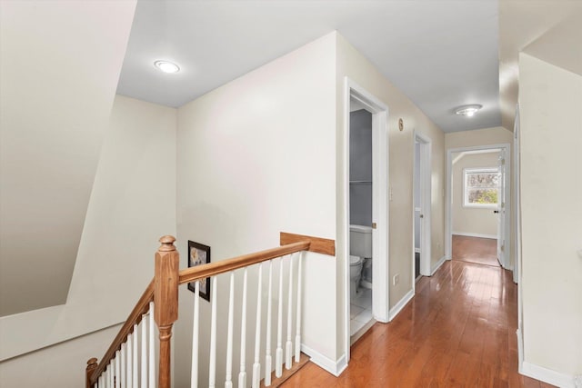 hallway featuring wood-type flooring, baseboards, and an upstairs landing