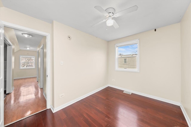 unfurnished room with a wealth of natural light, visible vents, hardwood / wood-style floors, and a ceiling fan