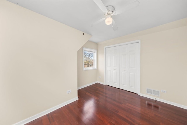 unfurnished bedroom featuring a closet, a ceiling fan, visible vents, wood finished floors, and baseboards