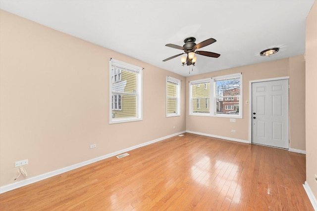 empty room featuring light wood-style floors, visible vents, baseboards, and a ceiling fan