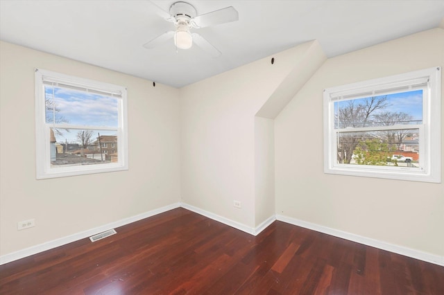 additional living space with wood finished floors, baseboards, visible vents, and a healthy amount of sunlight