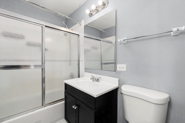 full bathroom with bath / shower combo with glass door, vanity, and toilet
