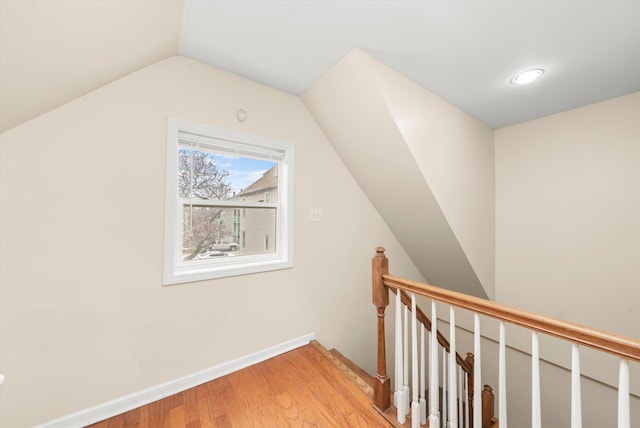 additional living space with light wood finished floors, baseboards, and vaulted ceiling