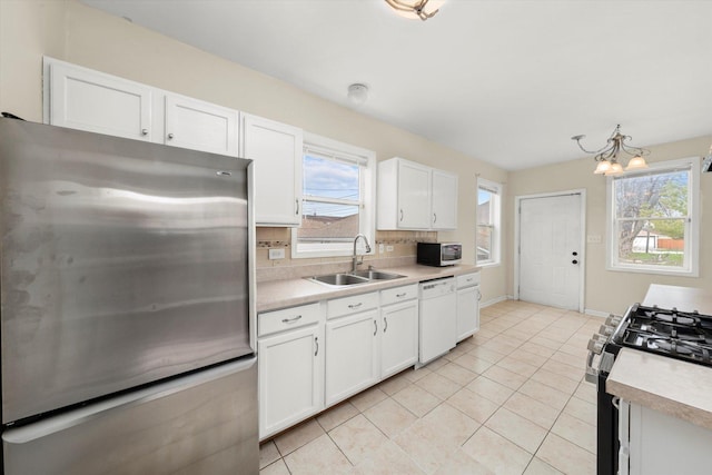 kitchen featuring tasteful backsplash, a sink, light countertops, appliances with stainless steel finishes, and white cabinetry