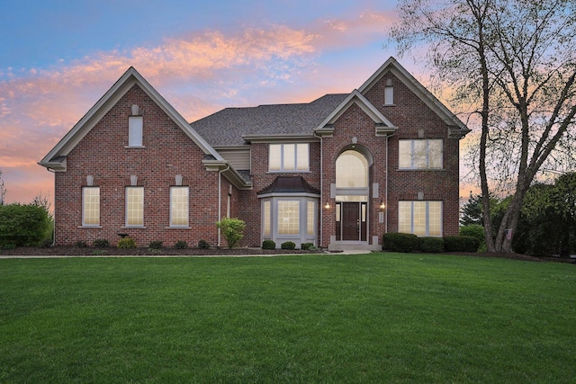 traditional-style house featuring a lawn and brick siding