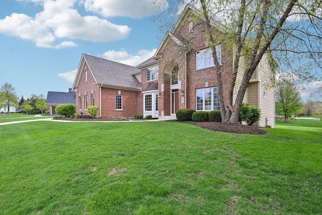 traditional-style house featuring brick siding, a front lawn, and a shingled roof