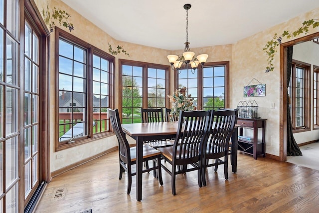 dining room with baseboards, a chandelier, wood finished floors, and plenty of natural light