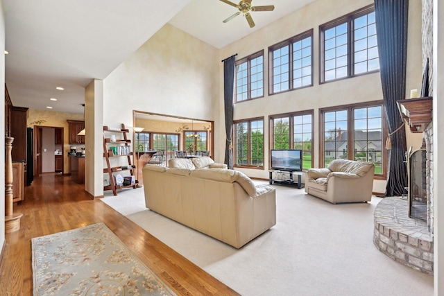 living room featuring a towering ceiling, light wood-style floors, a ceiling fan, and recessed lighting
