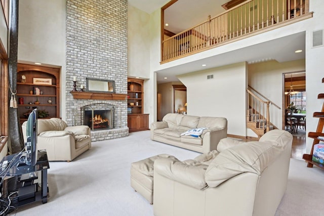 carpeted living room with a high ceiling, stairway, a brick fireplace, and built in features