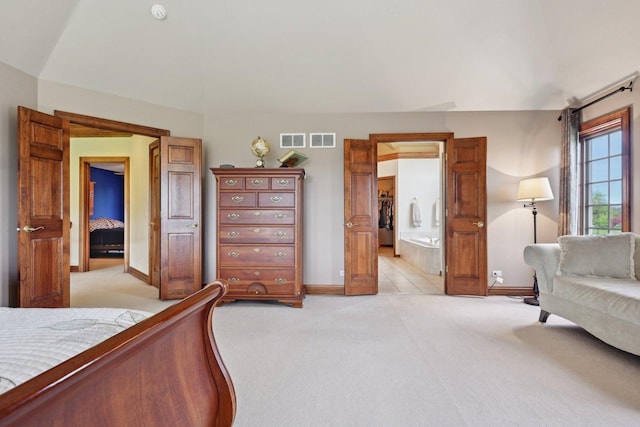 bedroom with light colored carpet, baseboards, and ensuite bath