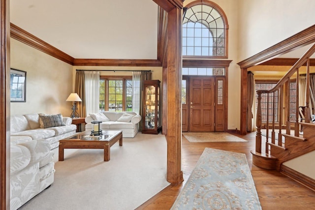 foyer featuring crown molding, stairway, wood finished floors, baseboards, and a high ceiling