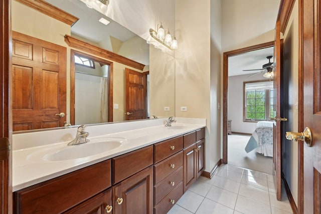 ensuite bathroom with double vanity, tile patterned floors, a ceiling fan, and baseboards