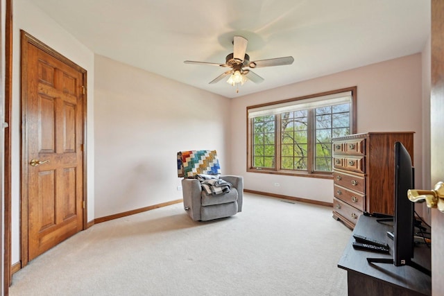 sitting room featuring baseboards, light carpet, and a ceiling fan