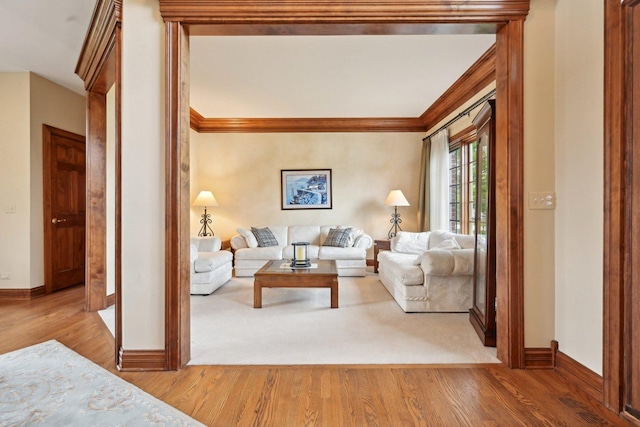 living area featuring wood finished floors, baseboards, and crown molding