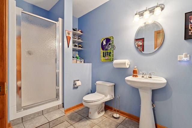 full bathroom with a stall shower, baseboards, tile patterned floors, toilet, and a sink