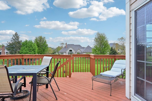 wooden terrace with outdoor dining space and a lawn