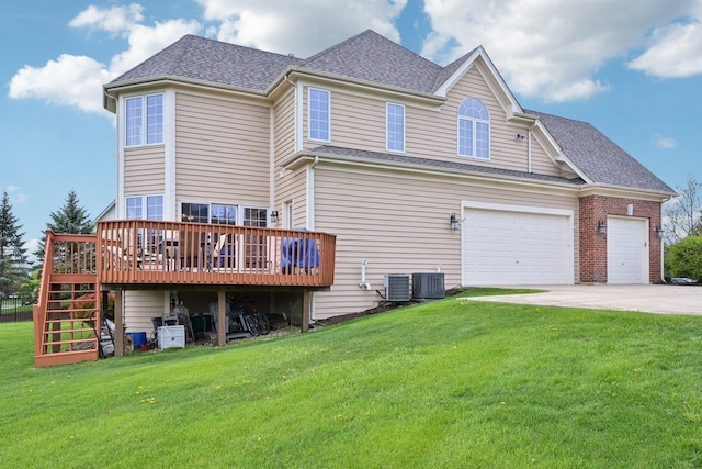 rear view of house featuring a wooden deck, a lawn, concrete driveway, stairway, and roof with shingles