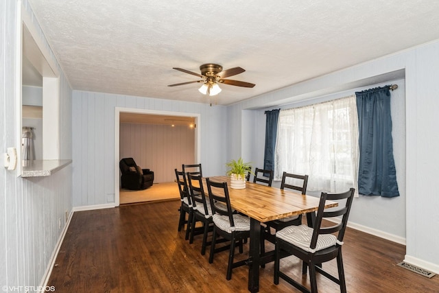 dining space with a textured ceiling, a ceiling fan, visible vents, wood finished floors, and baseboards