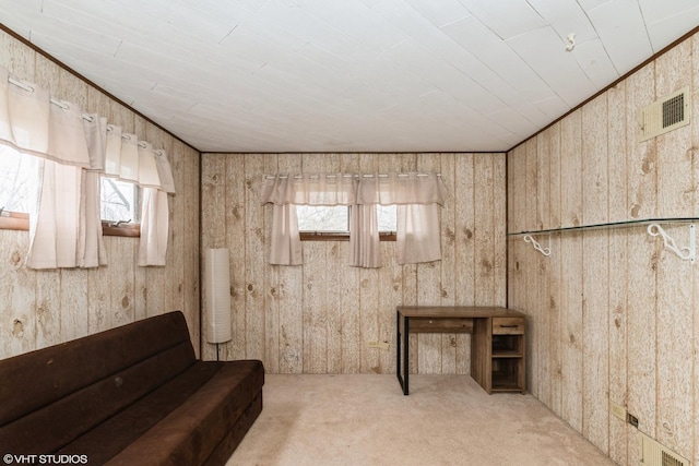 sitting room with carpet flooring, visible vents, and wooden walls