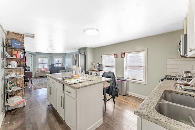 4026 N Kimball Ave, Chicago, IL 60618 - kitchen with a sink, dark wood-style flooring, a breakfast bar, appliances with stainless steel finishes, and a kitchen island