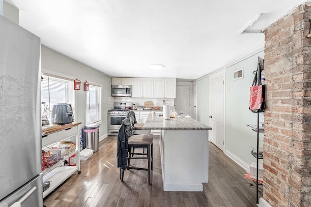 4026 N Kimball Ave, Chicago, IL 60618 - kitchen with stainless steel appliances, visible vents, hardwood / wood-style flooring, and a breakfast bar