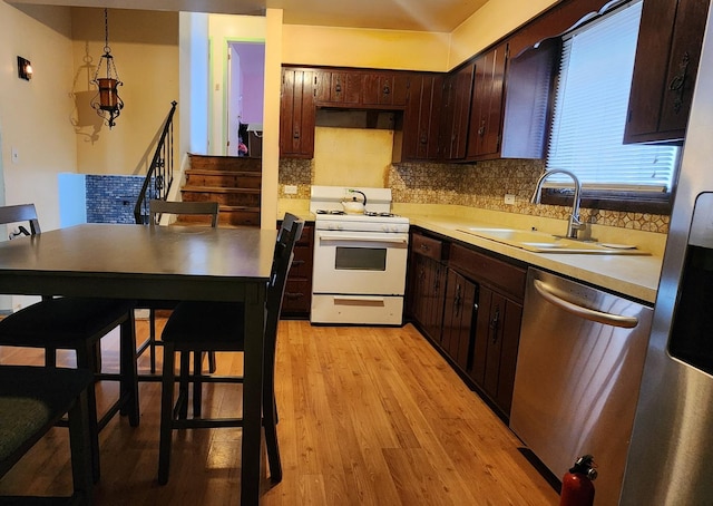 18454 Ridgewood Ave, Lansing, IL 60438 - kitchen with white gas range, stainless steel dishwasher, a sink, light countertops, and decorative backsplash