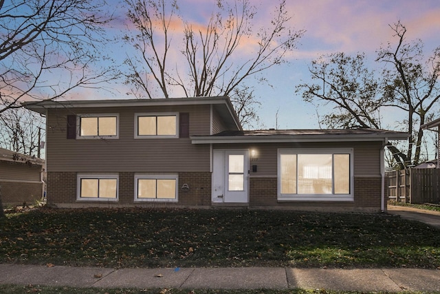 view of front of property featuring a front yard, fence, and brick siding