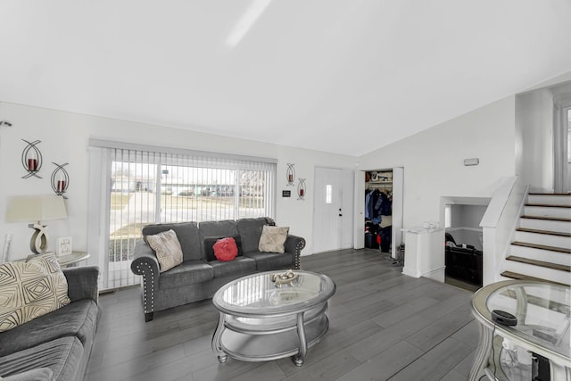 living room with dark wood-type flooring, stairs, and lofted ceiling