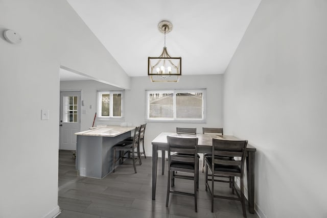 dining room featuring baseboards, a chandelier, wood finished floors, and lofted ceiling