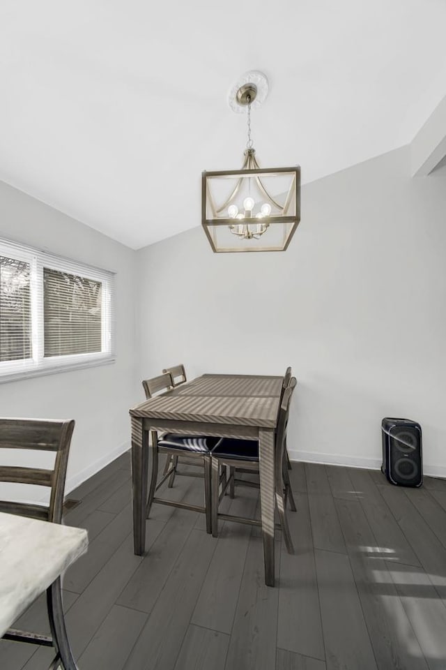 dining space with dark wood-type flooring, baseboards, and a chandelier
