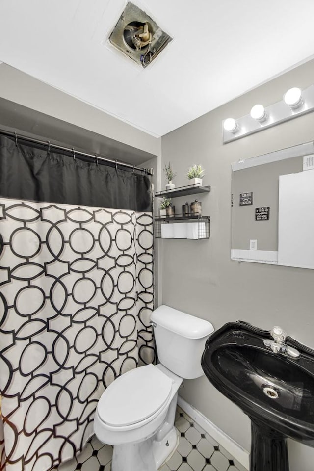 bathroom with baseboards, a shower with shower curtain, a sink, toilet, and tile patterned floors