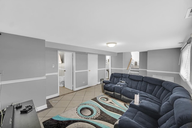 living room featuring light tile patterned flooring, baseboards, visible vents, and stairway