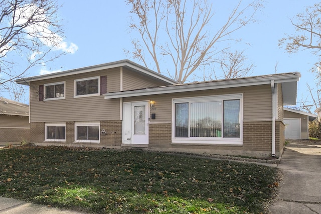 tri-level home with a garage, a front yard, and brick siding