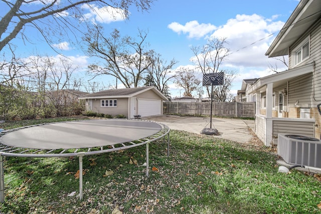 view of yard with central AC unit, a patio area, a detached garage, fence, and an outbuilding