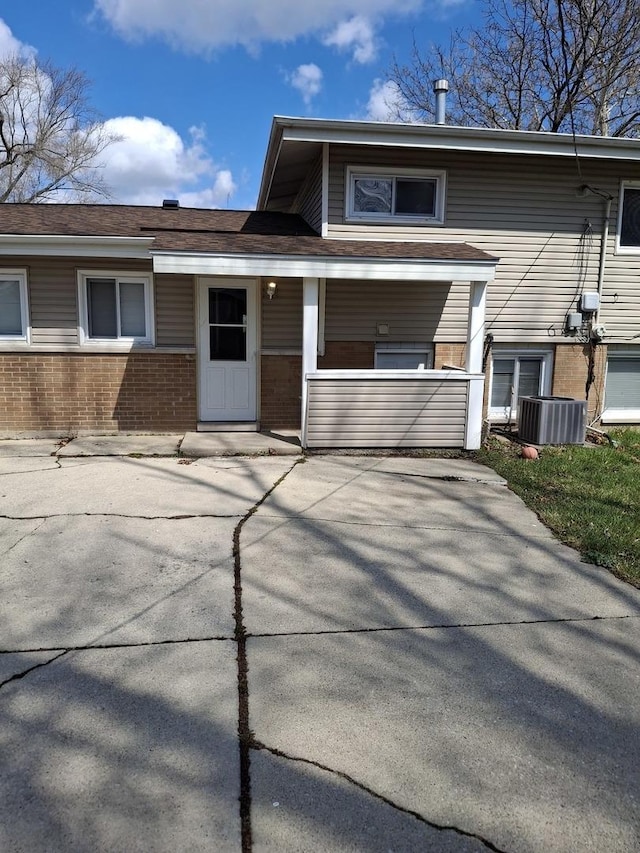 view of front of home featuring brick siding, central AC unit, and covered porch