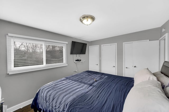 bedroom featuring multiple closets, wood finished floors, and baseboards