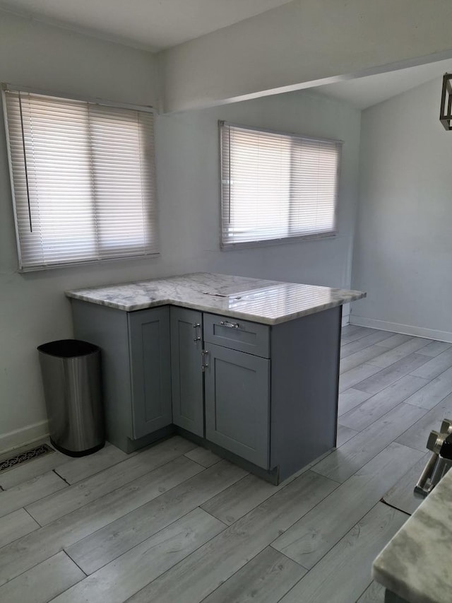 kitchen with gray cabinetry, light wood-style flooring, baseboards, and visible vents