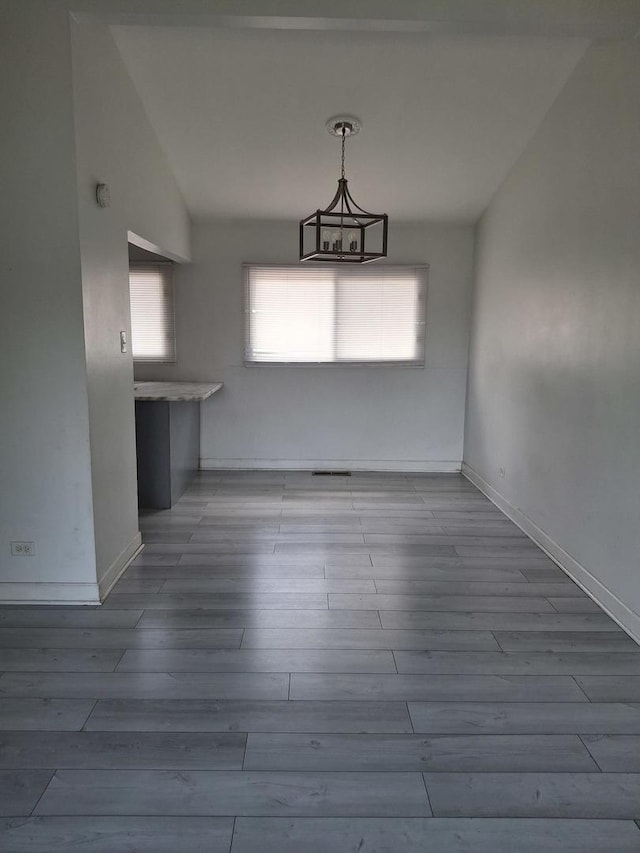unfurnished dining area with plenty of natural light, baseboards, and wood finished floors