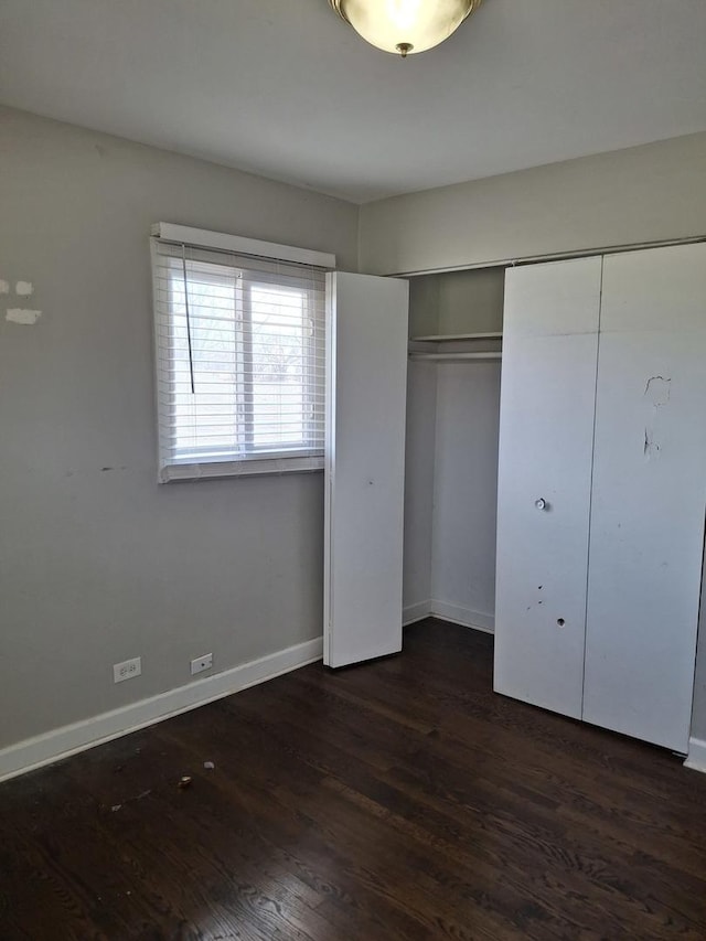 unfurnished bedroom featuring a closet, baseboards, and dark wood finished floors