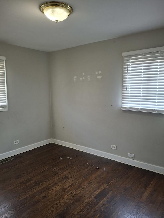 empty room with wood finished floors, baseboards, and plenty of natural light