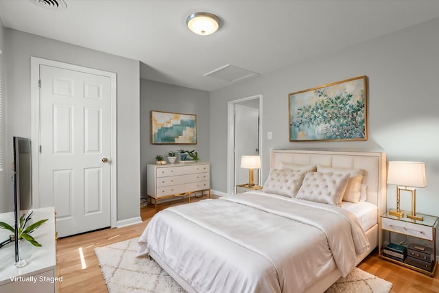 bedroom with light wood-style floors and attic access