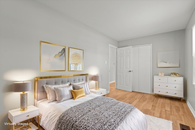 bedroom featuring light wood-type flooring, a closet, baseboards, and visible vents