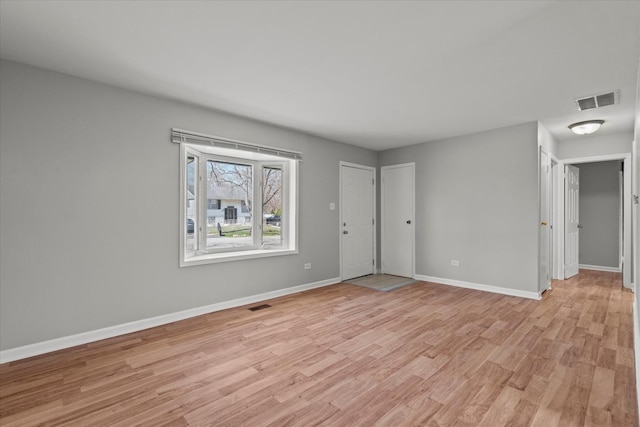 interior space with light wood-style floors, baseboards, and visible vents