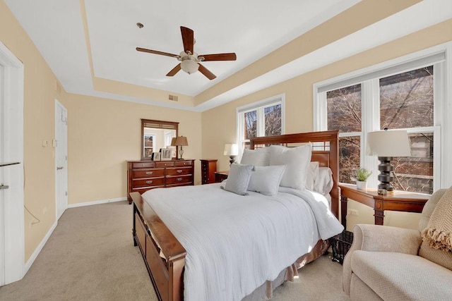 bedroom featuring baseboards, visible vents, light colored carpet, a ceiling fan, and a raised ceiling