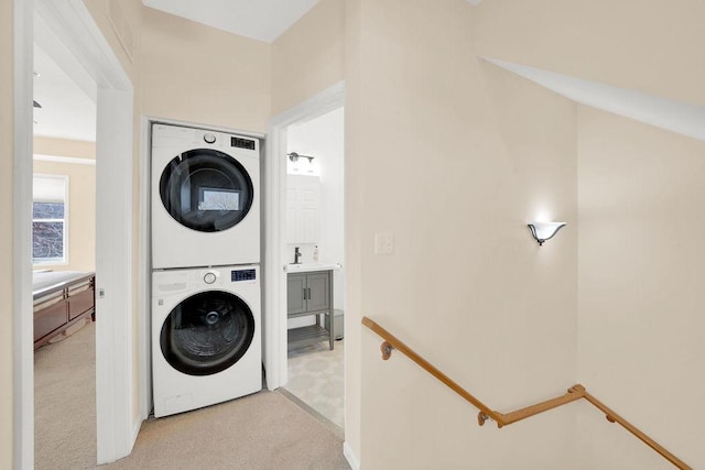 laundry area with light colored carpet, stacked washer / drying machine, and laundry area
