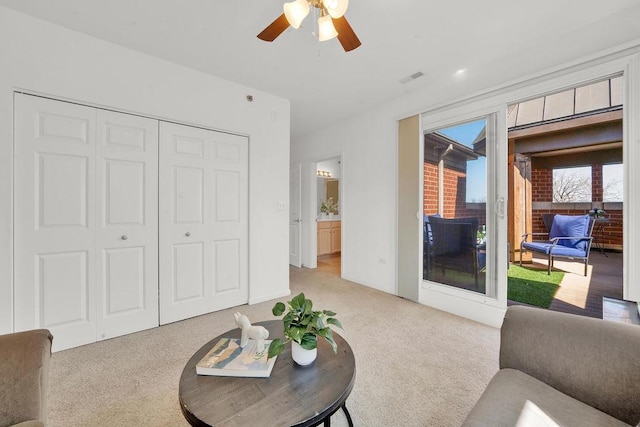 living room with light carpet, visible vents, and ceiling fan